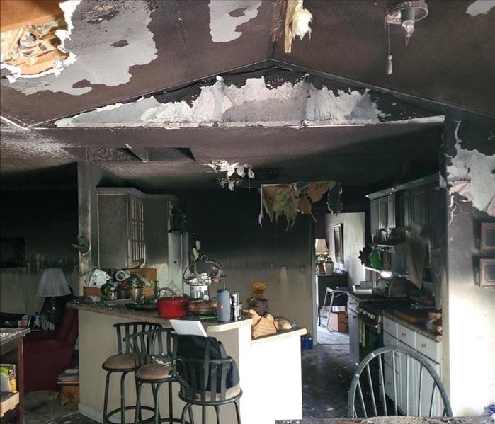 Burned home, hanging ceiling material and debris in kitchen